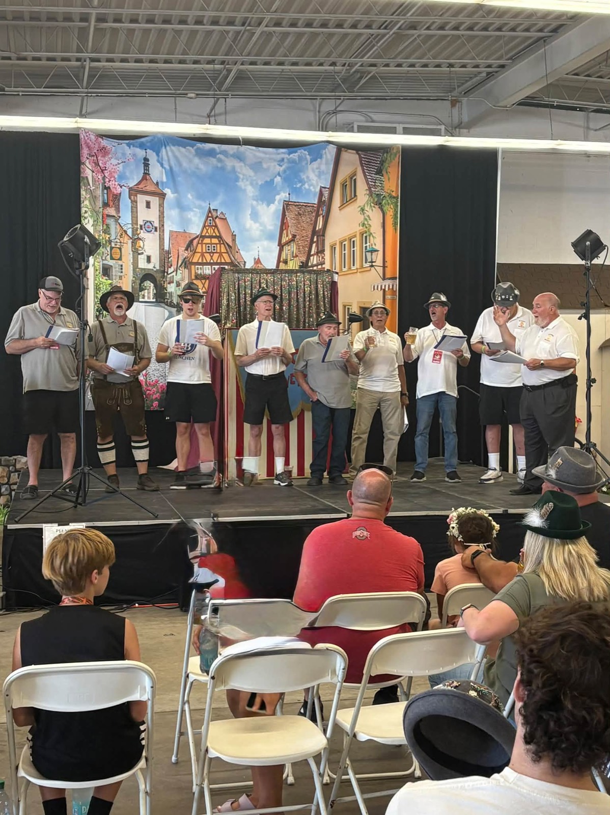 The Cleveland Maennerchor Men's Choir performing on stage at Cleveland Oktoberfest in Berea, several singers in lederhosen and alpine hats